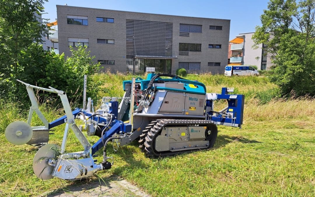 Rasenmäher-Roboter bei der Arbeit auf grüner Fläche vor einem modernen Gebäude an einem sonnigen Tag.