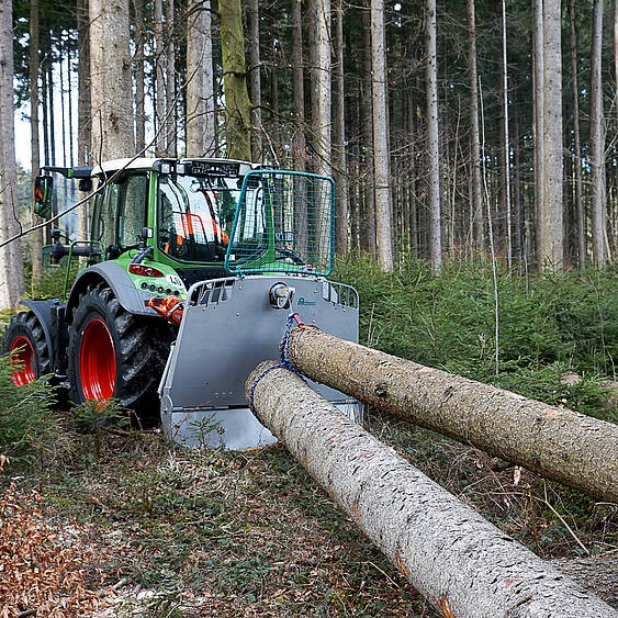 Traktor zieht Baumstämme im Wald mit Seilwinde, Holzwirtschaft, nachhaltige Forstwirtschaft.