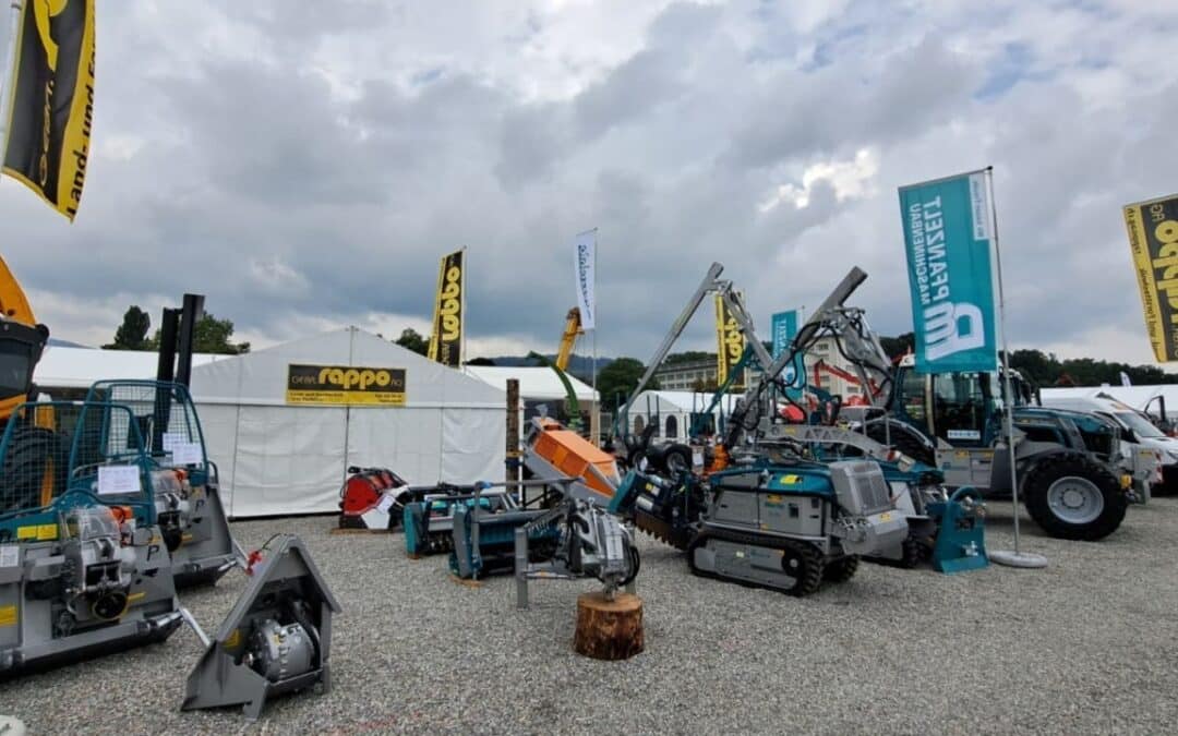 Ausstellung von Bau- und Landmaschinen mit Rappo-Stand auf einer Fachmesse unter bewölktem Himmel.