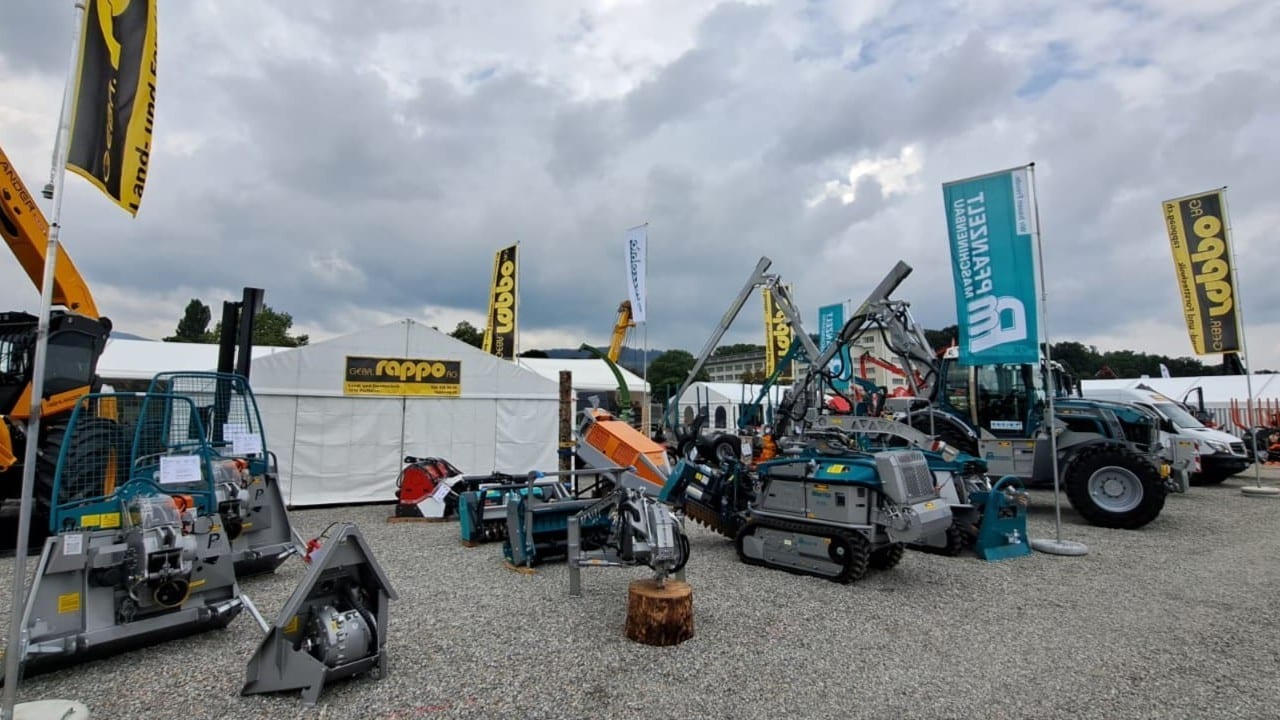 Ausstellung von Bau- und Landmaschinen mit Rappo-Stand auf einer Fachmesse unter bewölktem Himmel.