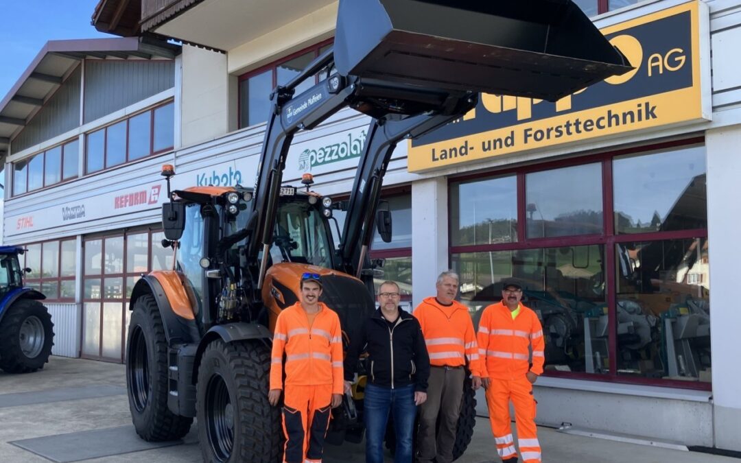 Männer in Arbeitskleidung vor einem großen Traktor bei einem Landtechnik-Geschäft.