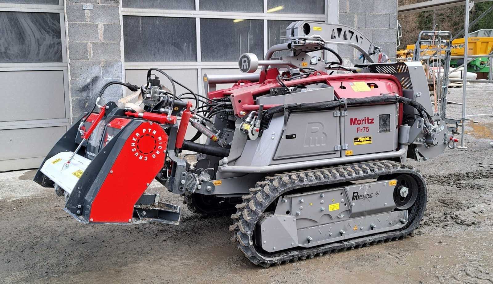 Raupenfahrzeug Moritz Fr75 vor einer Garage, ausgestattet mit PTM Microcrusher für Bauarbeiten im Freien.