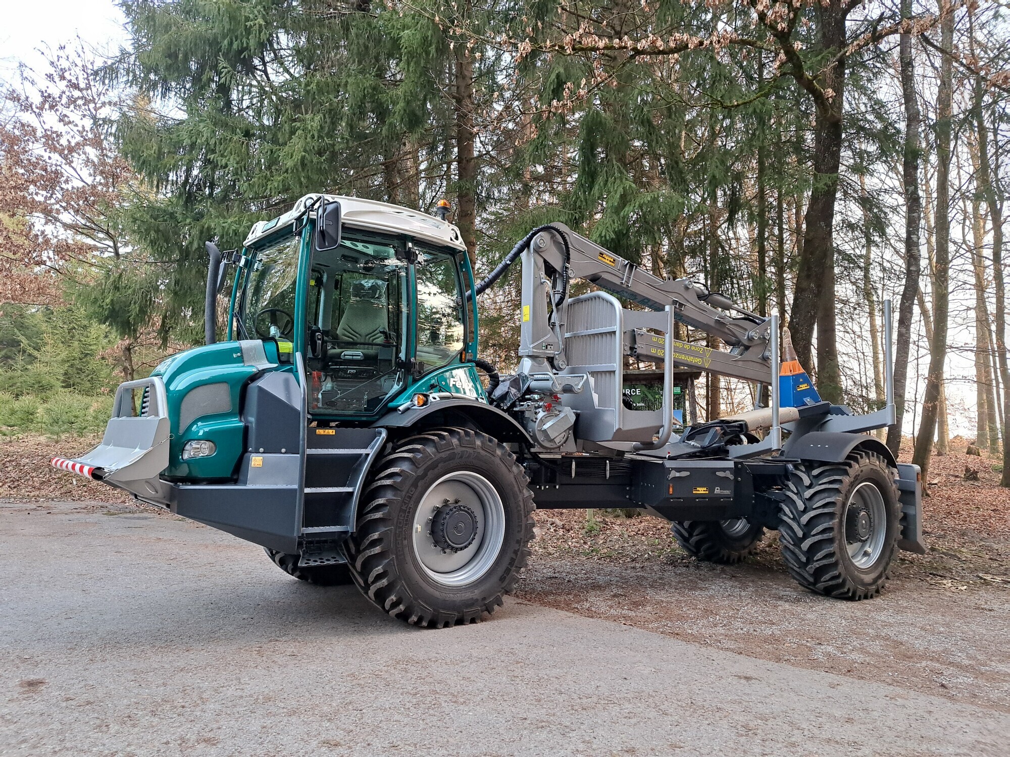 Moderner Forsttraktor mit Kran im Wald bei Tageslicht, bereit für schwere Holzarbeiten in der Forstwirtschaft.
